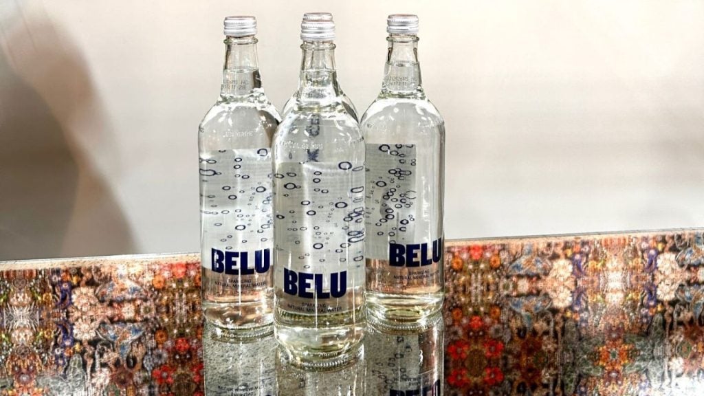 Clear glass water bottles on multicoloured table.