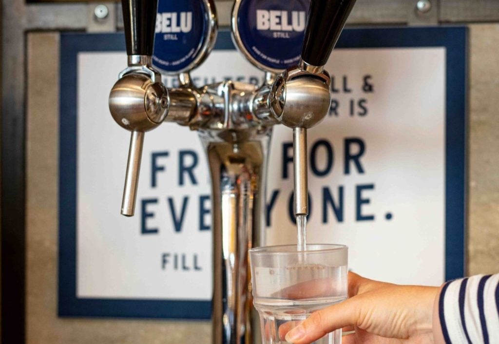 water filtration taps, with person holding glass underneath tap.